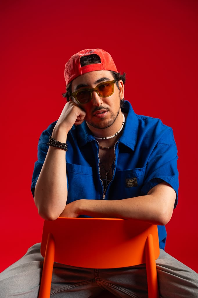 Andrew Aoun in a blue work jacket seated on an orange chair