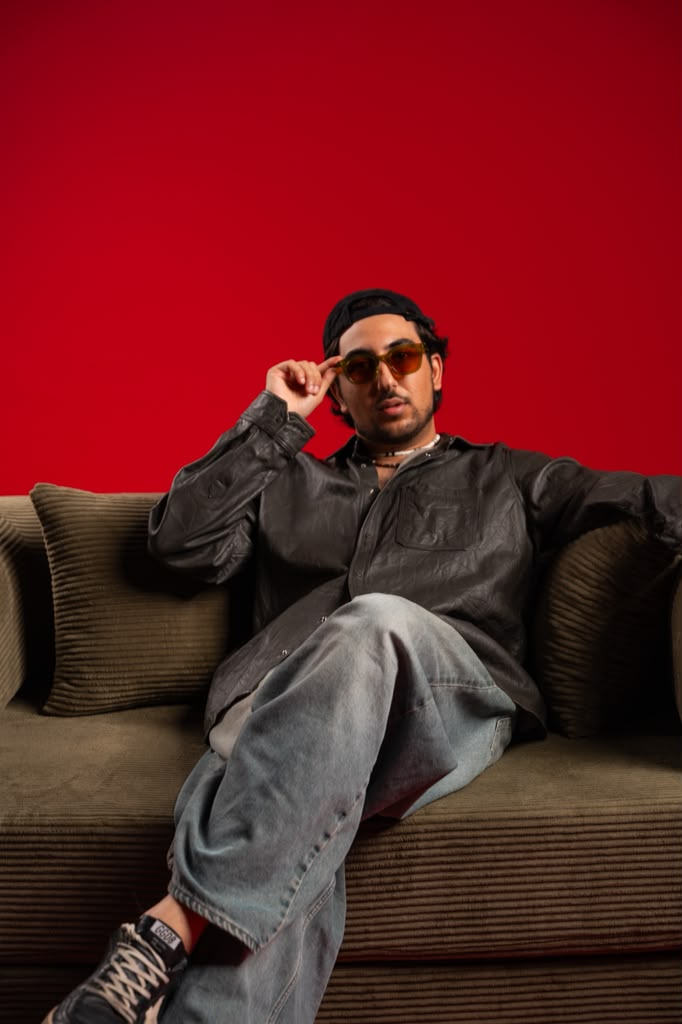Andrew Aoun in a black leather shirt on an olive couch
